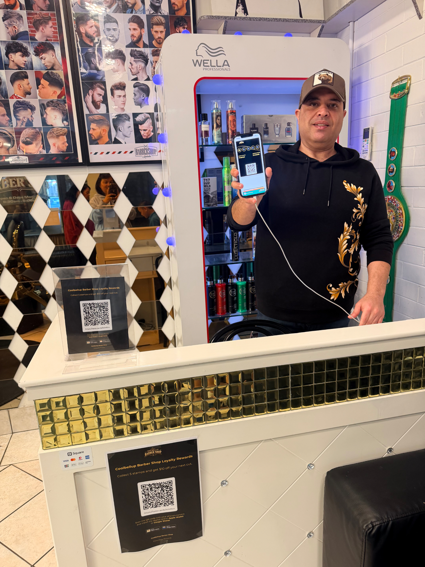 Alex, owner of Coolbellup Barber Shop in Perth, holding a phone showing his shop's Reviewify digital loyalty card